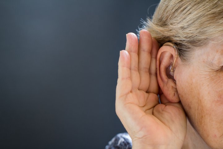 Persoon met gehoorapparaat luistert aandachtig, beeld voor hoe tinnitus en gehoorverlies samenhangen