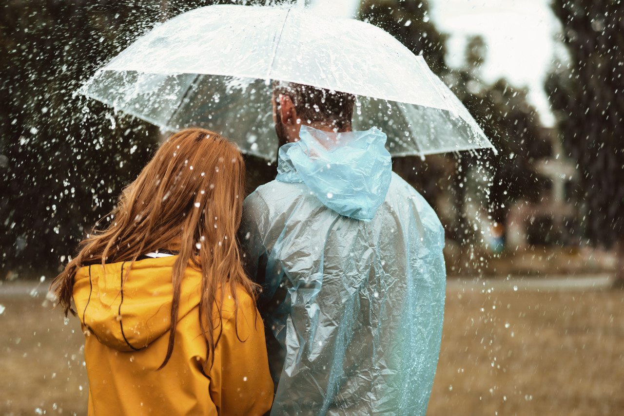 Twee mensen lopen onder een paraplu in de regen, symboo voor hoe weer en seizoenen stemming in tinnitus kunnen be&iuml;nvloeden